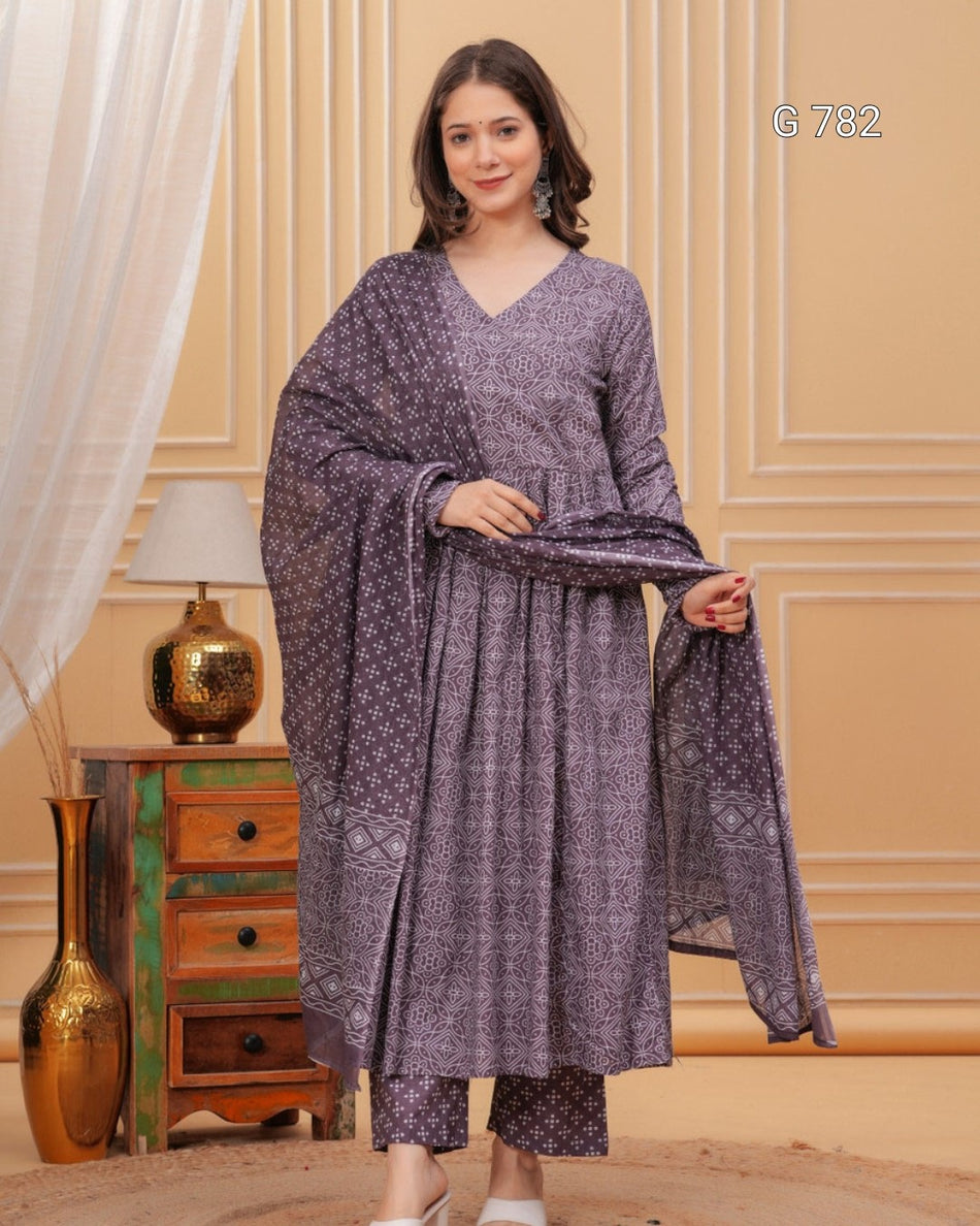 Woman wearing a patterned outfit with a matching shawl in a decorated room.