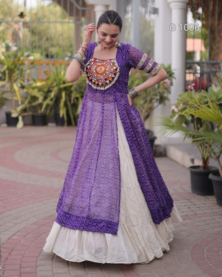 A woman wearing a traditional Indian outfit with a purple embroidered kurta and a white flared skirt, standing in an outdoor courtyard with potted plants.