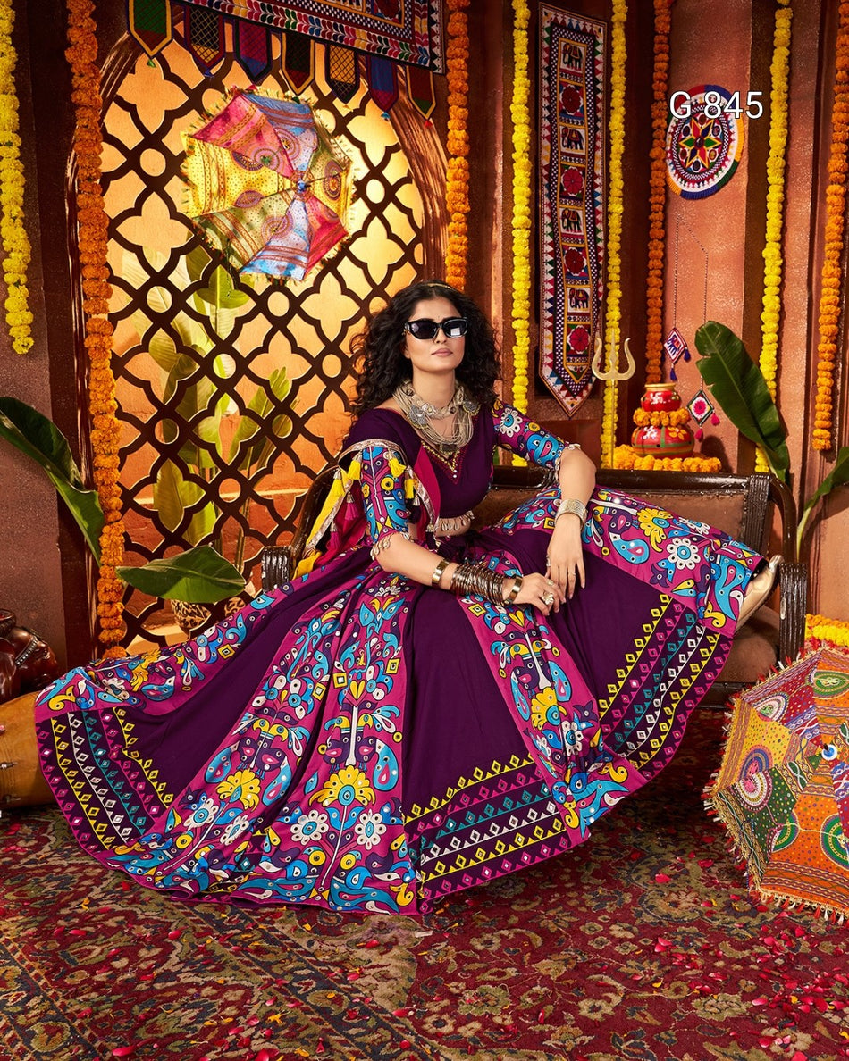 Woman in a colorful traditional outfit sitting in a decorated room with ornate wall art and decorations.