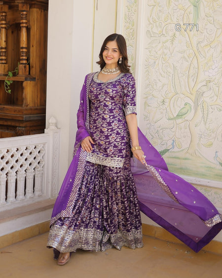 Woman wearing a purple traditional outfit with a matching dupatta in a decorated room.
