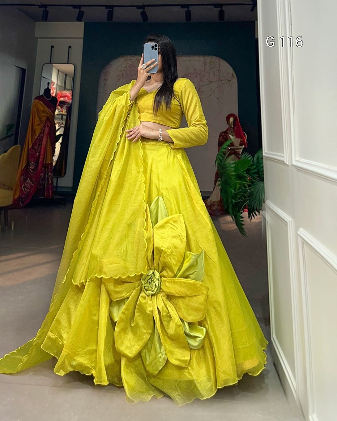 Person wearing a bright yellow traditional outfit with a large bow in a room.