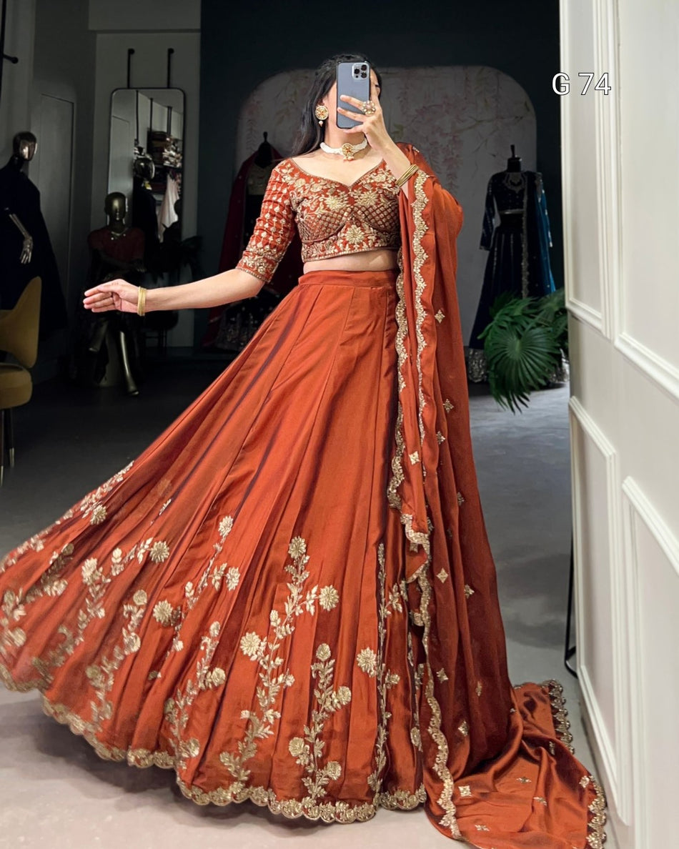 Person wearing a traditional orange lehenga with gold embroidery in a room setting.