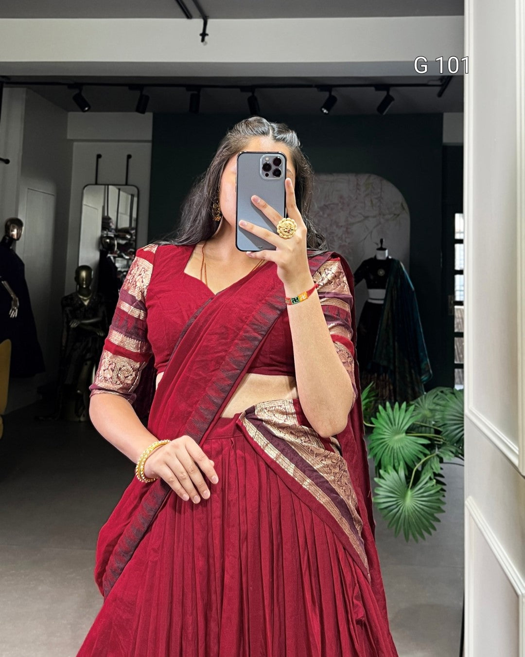 Woman in a red saree taking a mirror selfie in a store.