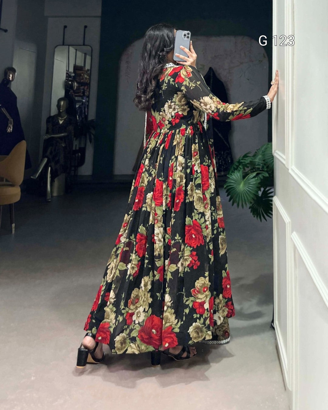 Woman taking a mirror selfie wearing a floral dress in a room.