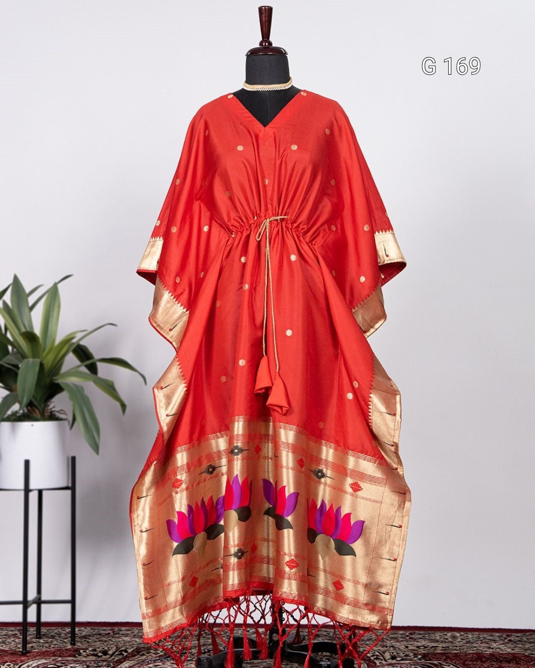 Red dress with gold and black floral patterns on a mannequin against a white background.