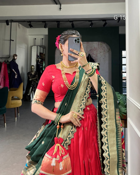 Person wearing a red saree with green border and gold jewelry in a store setting.