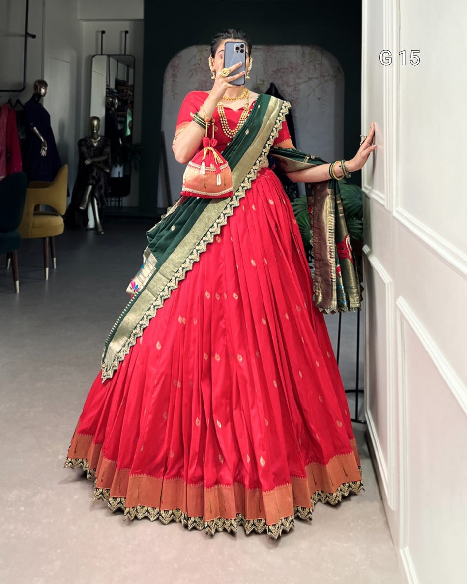 Person wearing a red saree with green and gold border in a room.