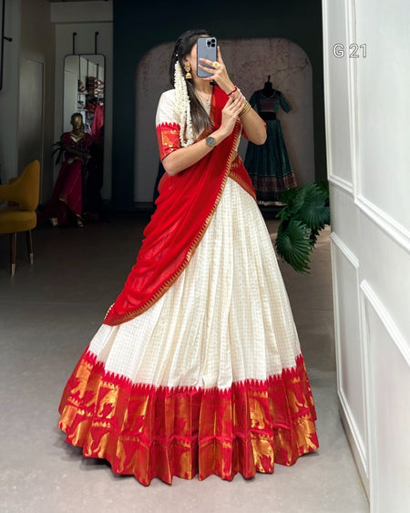 Woman wearing a red and white saree taking a mirror selfie in a room.