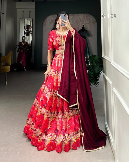Person wearing a red and maroon traditional outfit with a floral pattern, standing in a room.