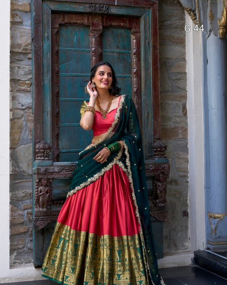 Woman in a red and green traditional outfit standing in front of a decorative door.