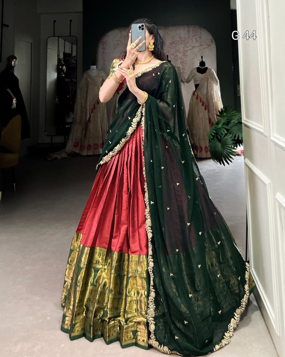 Person wearing a traditional green and red saree with gold border in a room.