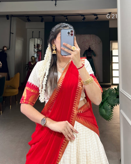 Person wearing a red and white saree taking a mirror selfie.