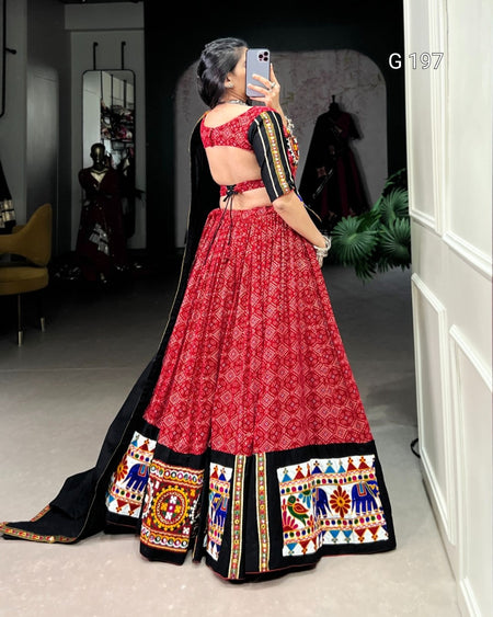 Person wearing a red and black traditional outfit with colorful patterns indoors.