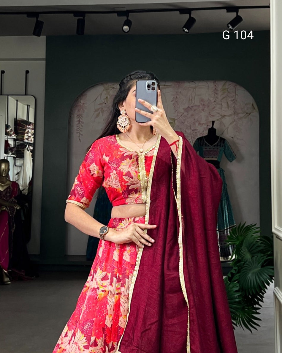 Woman in a red saree with floral patterns taking a mirror selfie in a store.