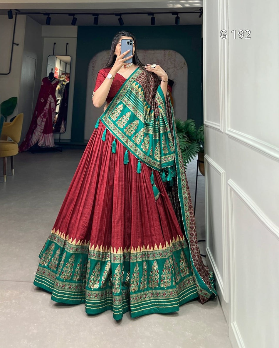 Woman wearing a red and green traditional outfit with a matching dupatta in a room.