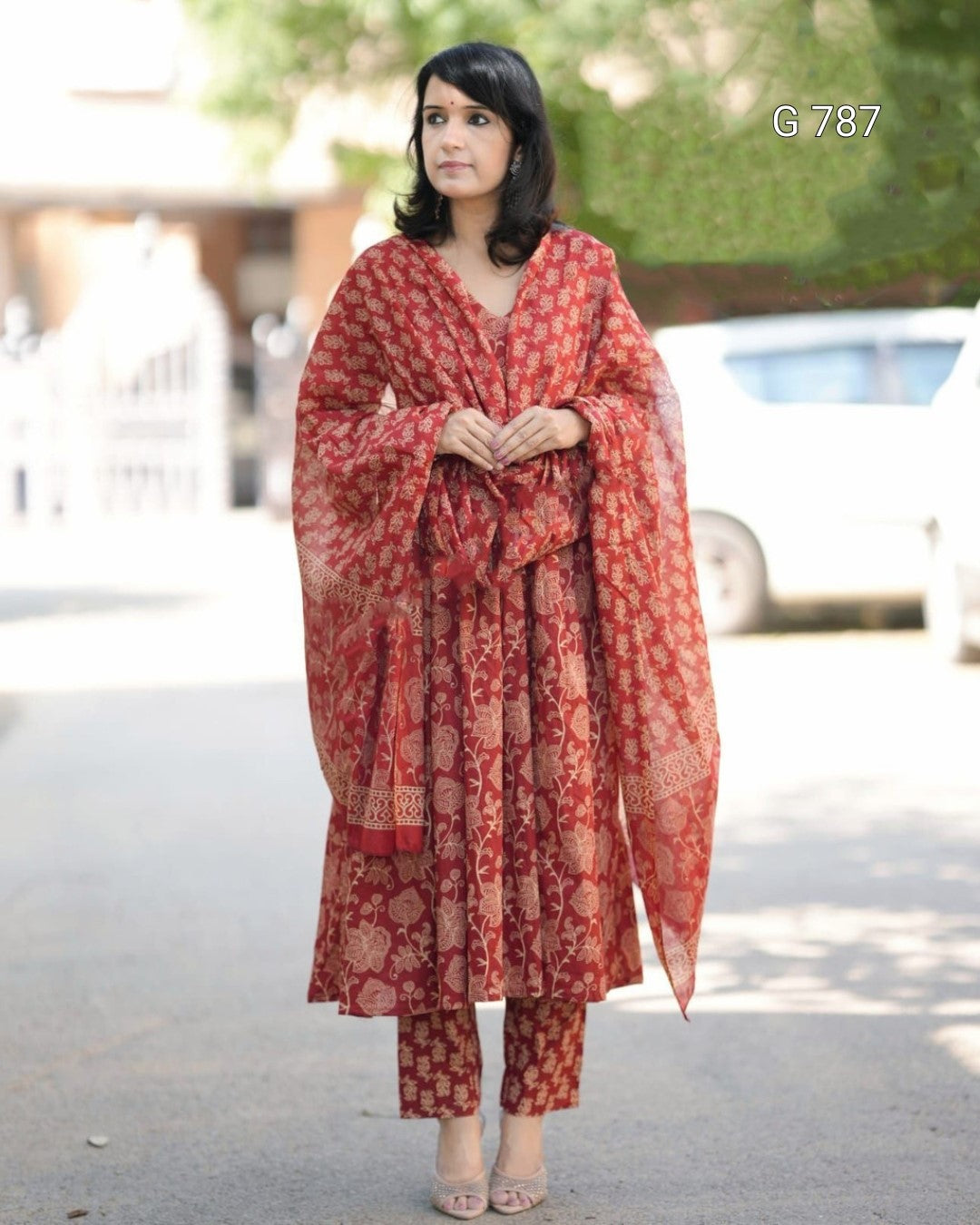 Woman wearing a red patterned outfit standing outdoors with blurred background