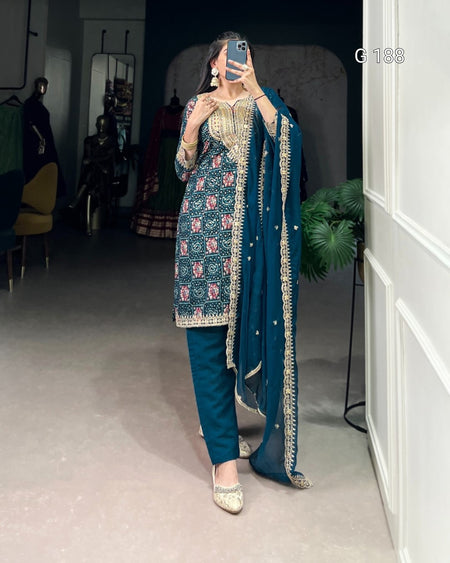 Person wearing a traditional outfit with a blue and gold design in an indoor setting.
