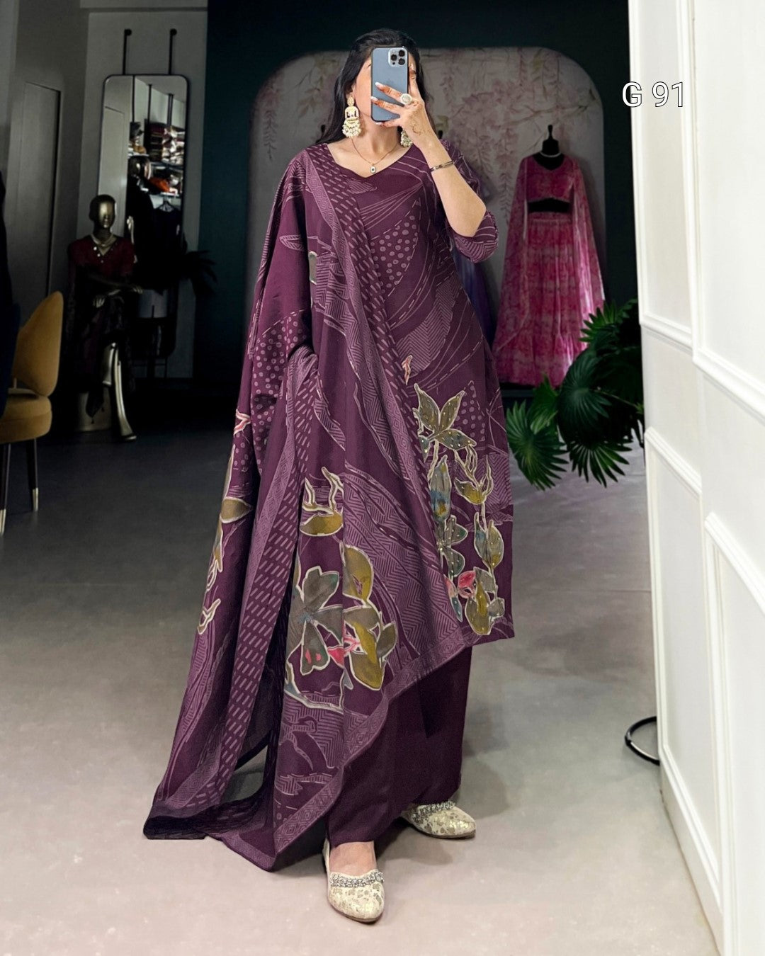 Woman wearing a purple traditional outfit with floral patterns in a room.