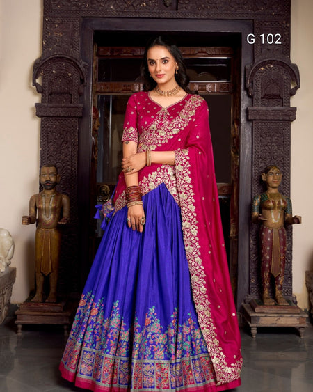 Woman in a traditional pink and blue saree with intricate patterns, standing in an ornate doorway.