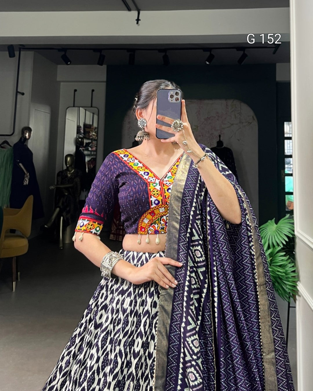 Person wearing a colorful traditional outfit with a patterned scarf in an indoor setting.