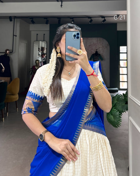 Woman taking a mirror selfie wearing a blue saree with a white blouse.