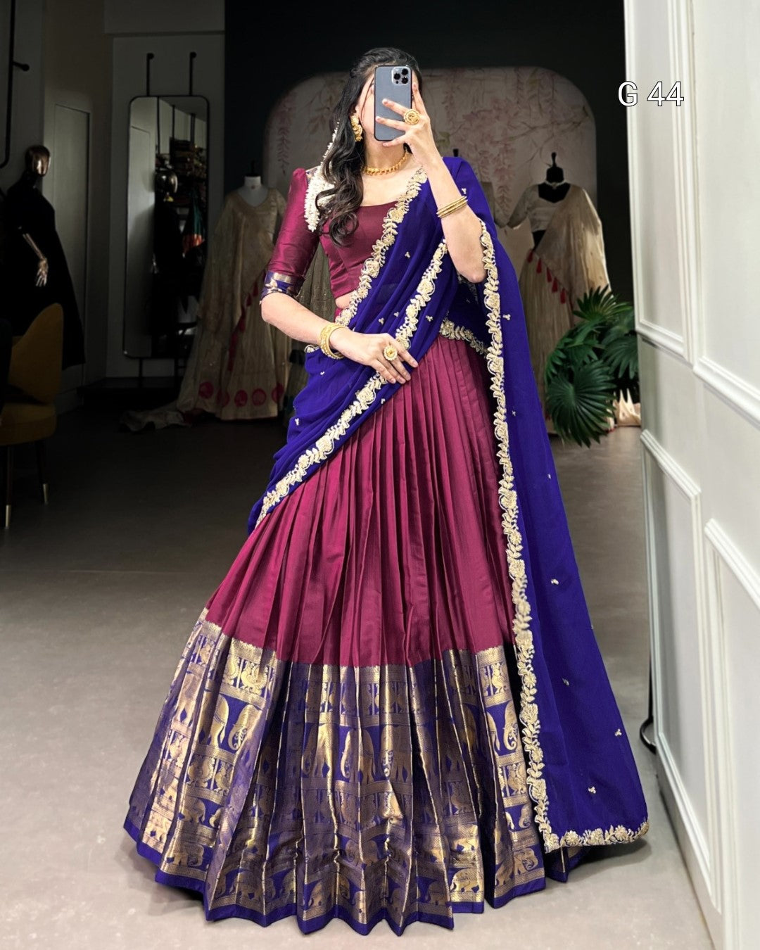 Woman wearing a traditional purple and blue saree in an indoor setting.