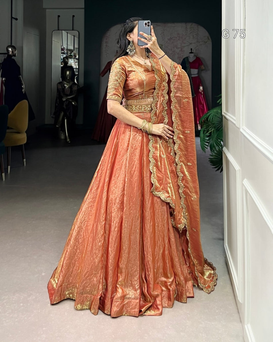 Woman in a peach saree with gold details taking a mirror selfie.