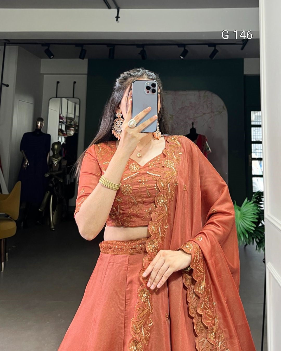 Person wearing a traditional outfit with intricate designs in a room setting.