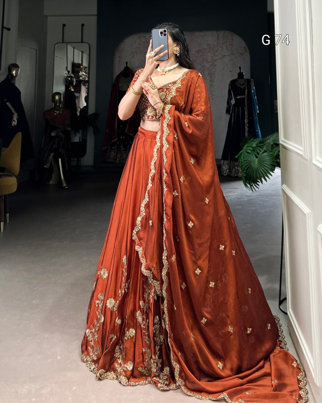 Person wearing a traditional orange saree with gold embroidery in a room setting.