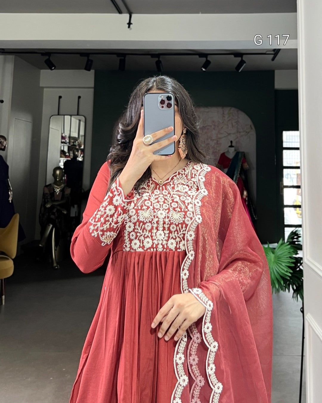 Person wearing a red dress with white lace details in a room.