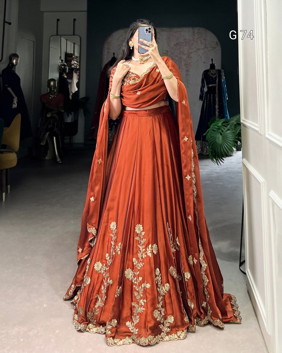 Person wearing a traditional orange embroidered outfit in a room with mannequins.