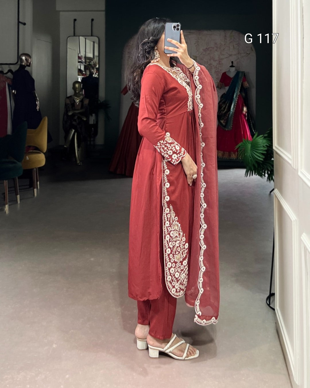 Woman wearing a red traditional outfit with white embroidery in a clothing store.