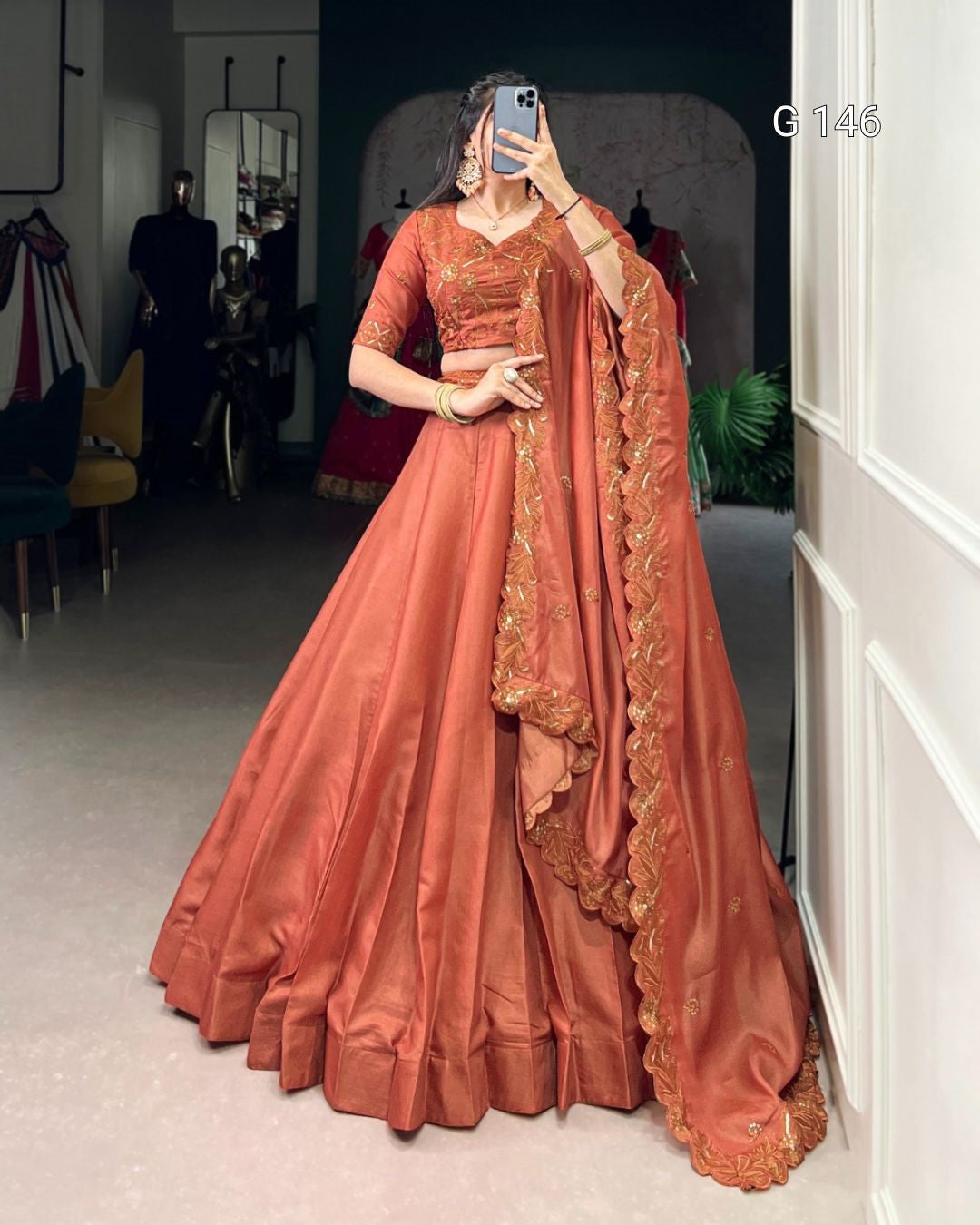 Person wearing a traditional orange outfit with gold details in a room.