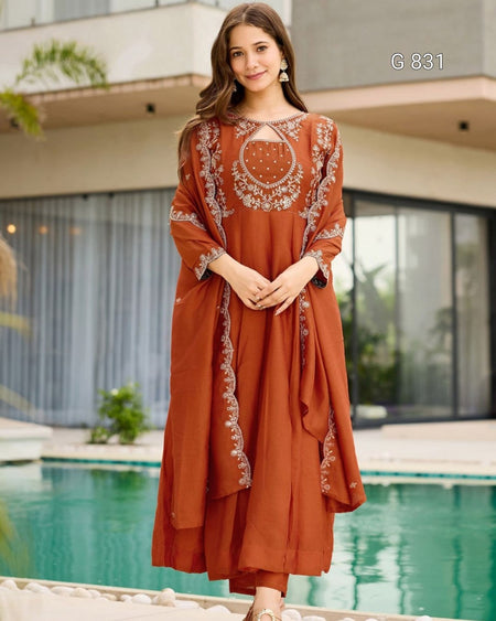 Woman wearing a rust-colored embroidered dress by a poolside.