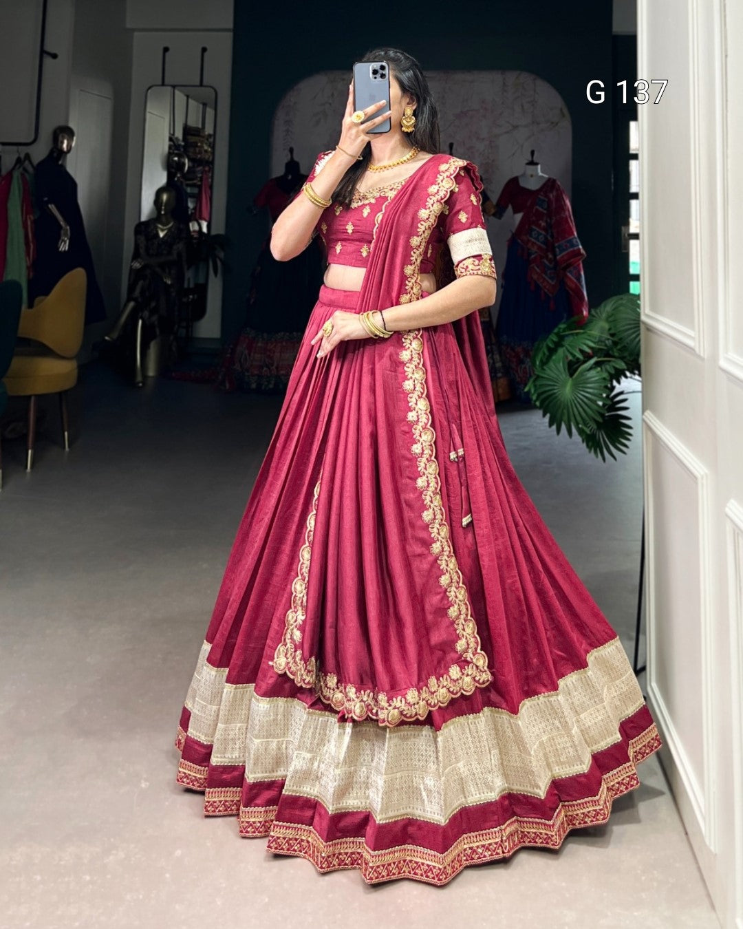 Woman wearing a traditional maroon and gold saree in a store setting.