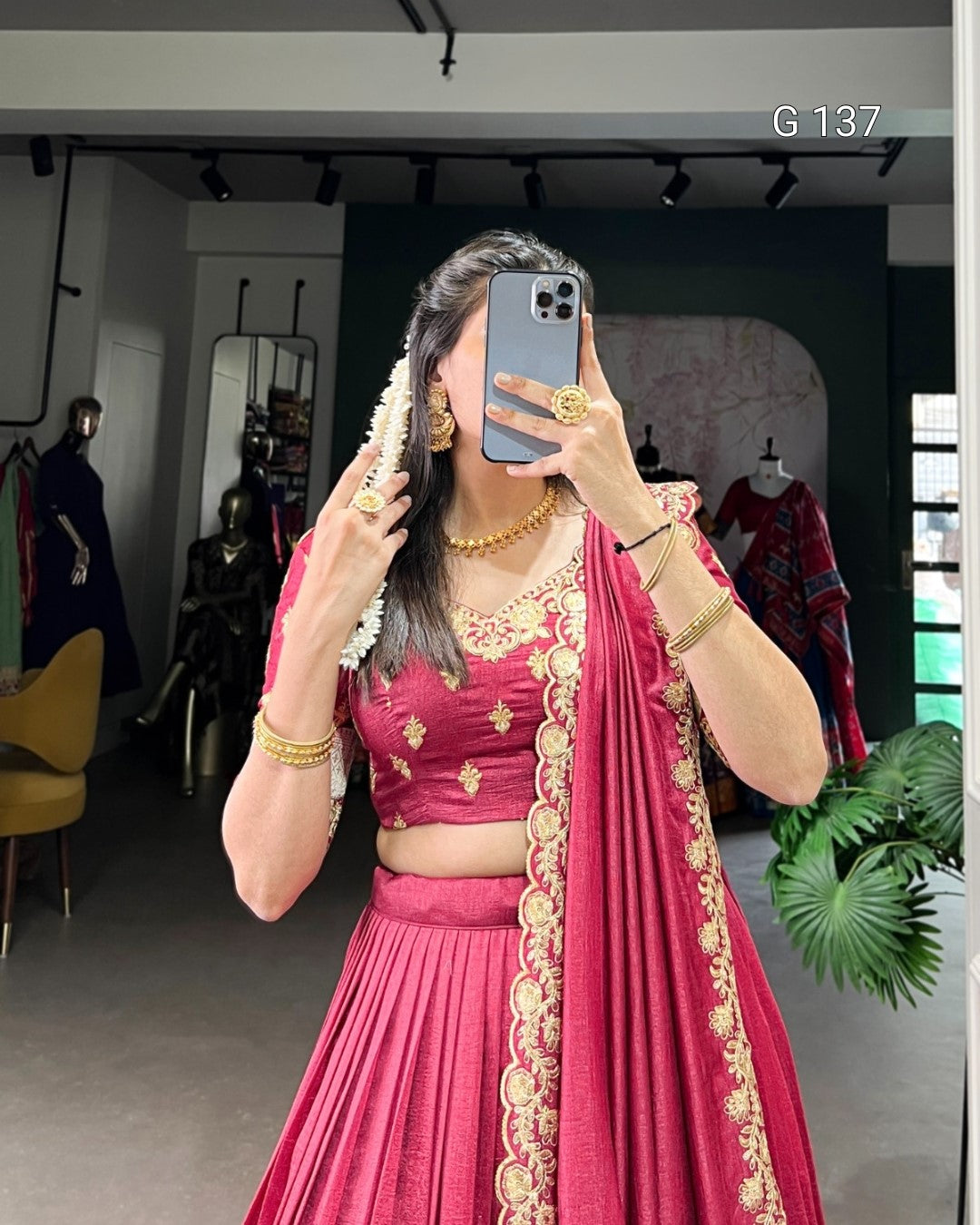 Person wearing a pink traditional outfit with gold embroidery, taking a mirror selfie.