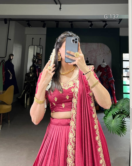 Person wearing a pink traditional outfit with gold embroidery, taking a mirror selfie.