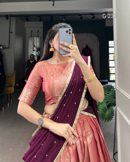 Woman taking a mirror selfie wearing a pink blouse and purple saree with gold border.