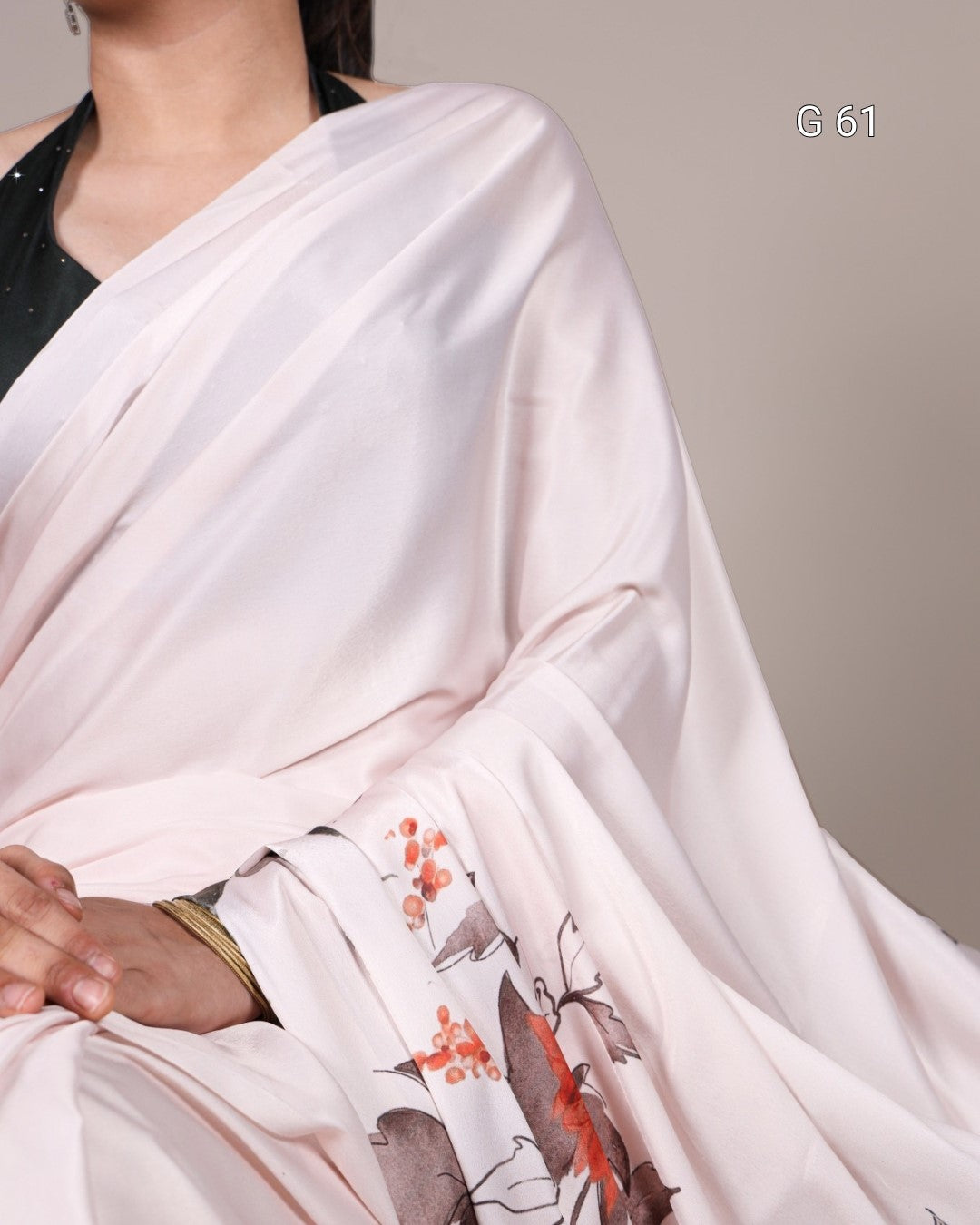 White saree with floral patterns draped over a person against a neutral background