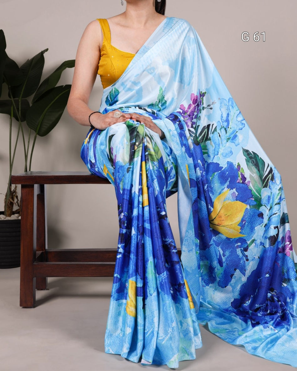 Woman holding a blue floral saree with a yellow blouse against a neutral background