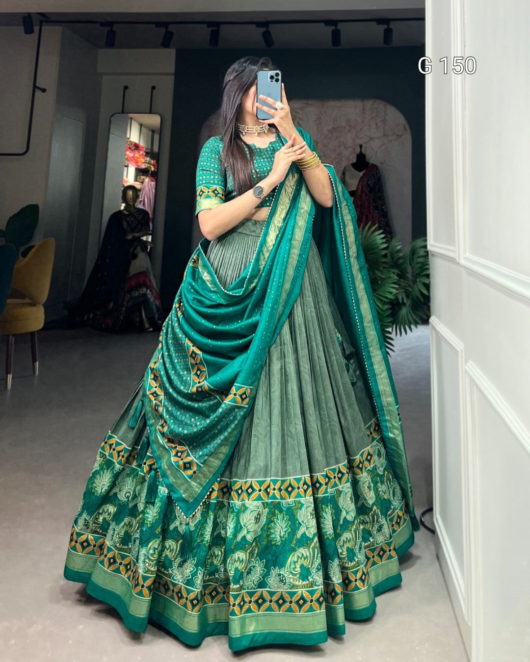 Woman wearing a green saree with a matching blouse in an indoor setting.