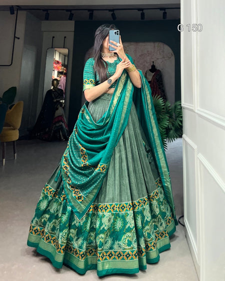 Woman wearing a green saree with a matching blouse in an indoor setting.