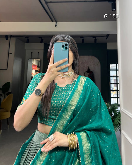 Person wearing a green saree with gold details indoors.