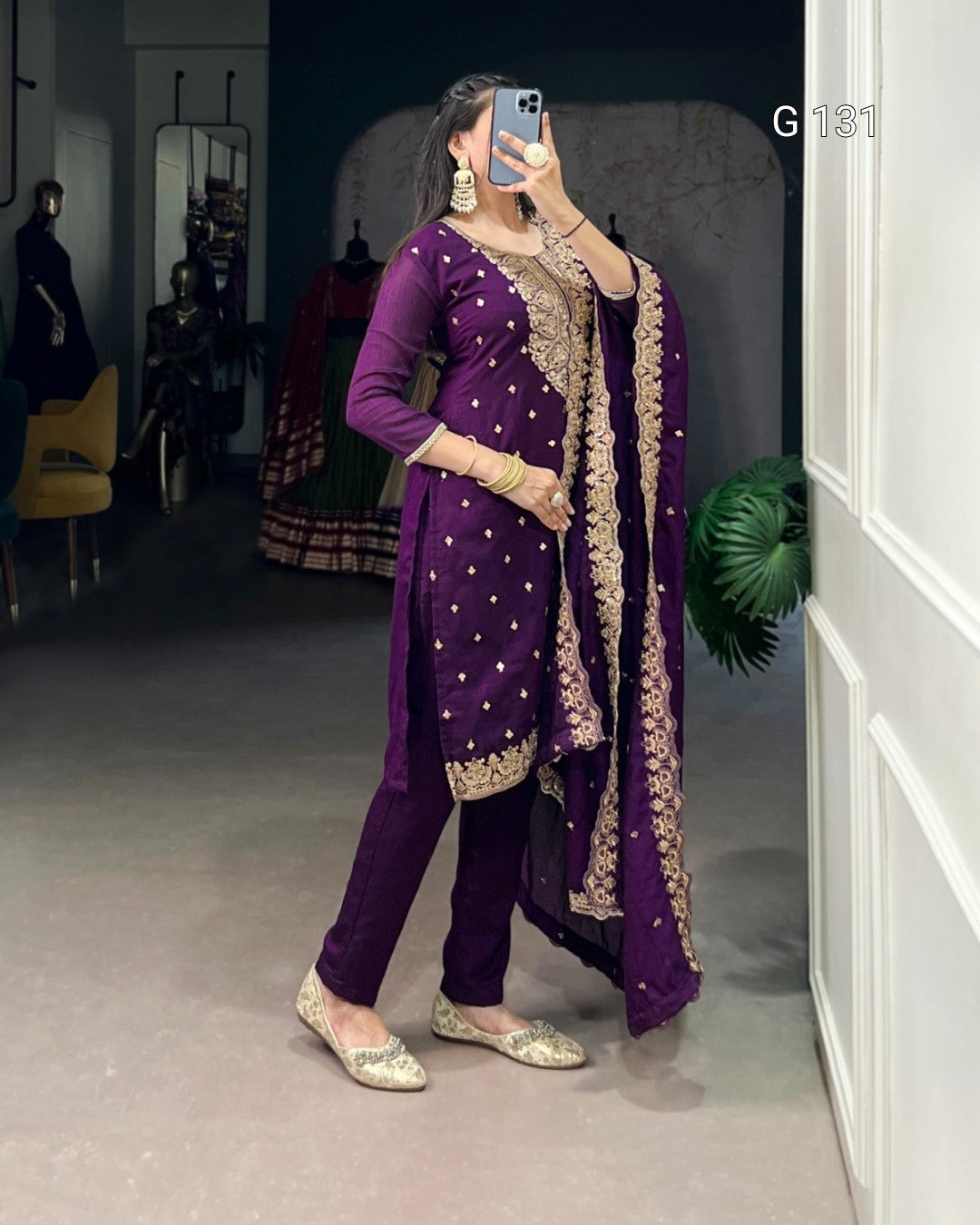 Woman in a traditional purple outfit with gold details taking a mirror selfie.