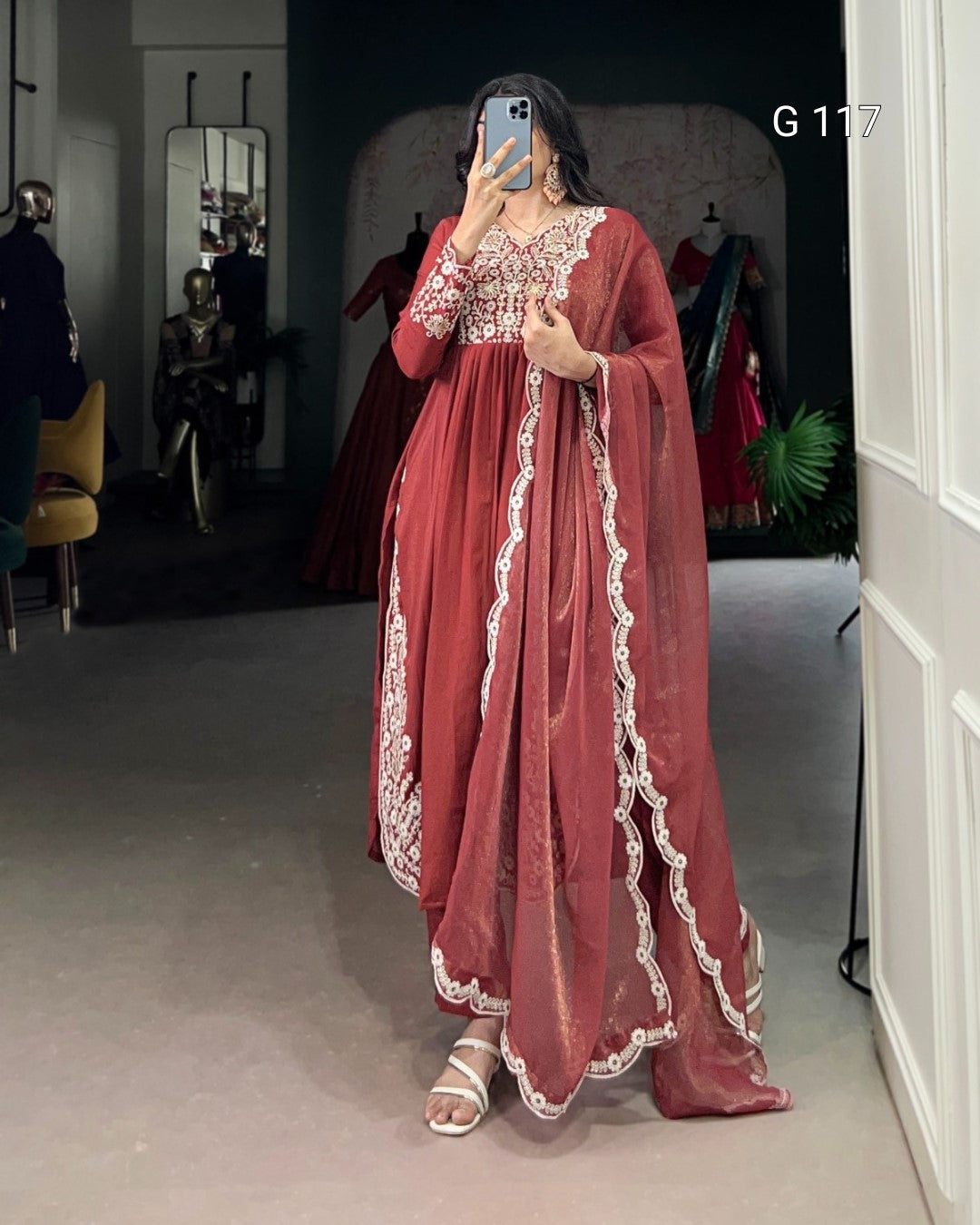 Person wearing a red embroidered dress in a room with mirrors and clothing.
