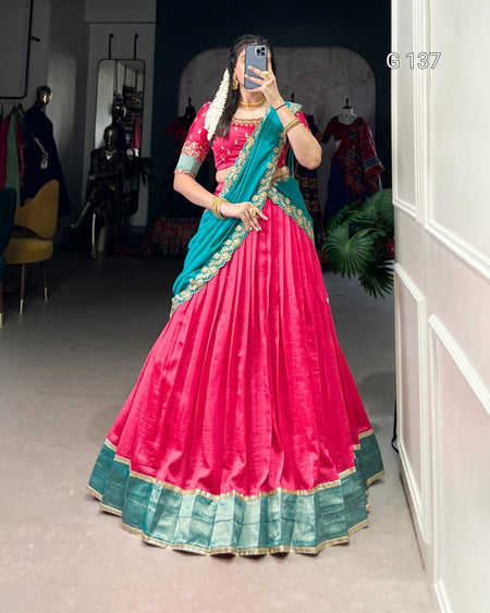 Person wearing a pink and blue traditional outfit in a room with clothing racks.