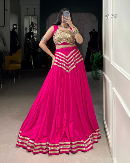 Person wearing a bright pink and gold traditional outfit in a room.