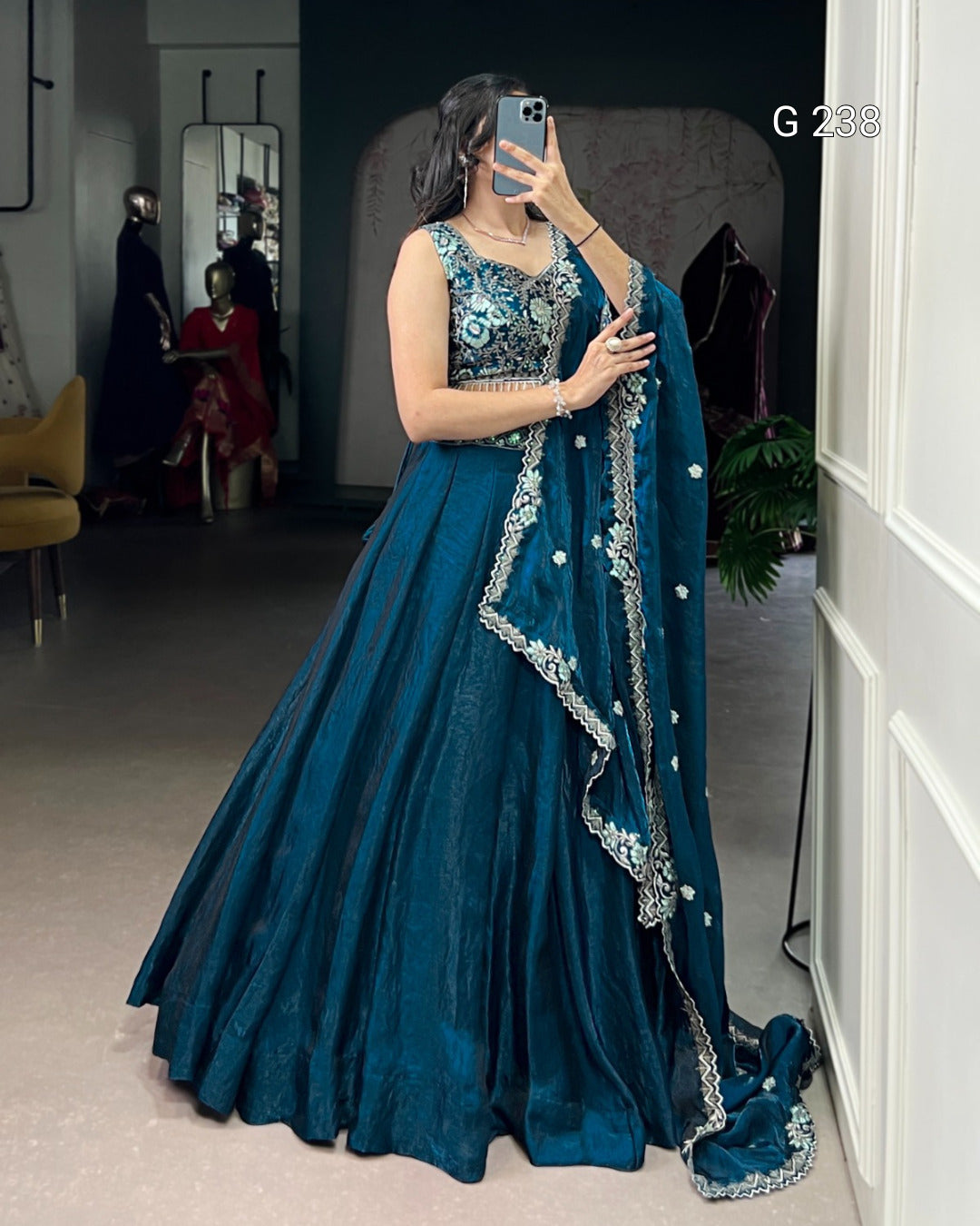 Woman in a blue embroidered saree standing indoors.
