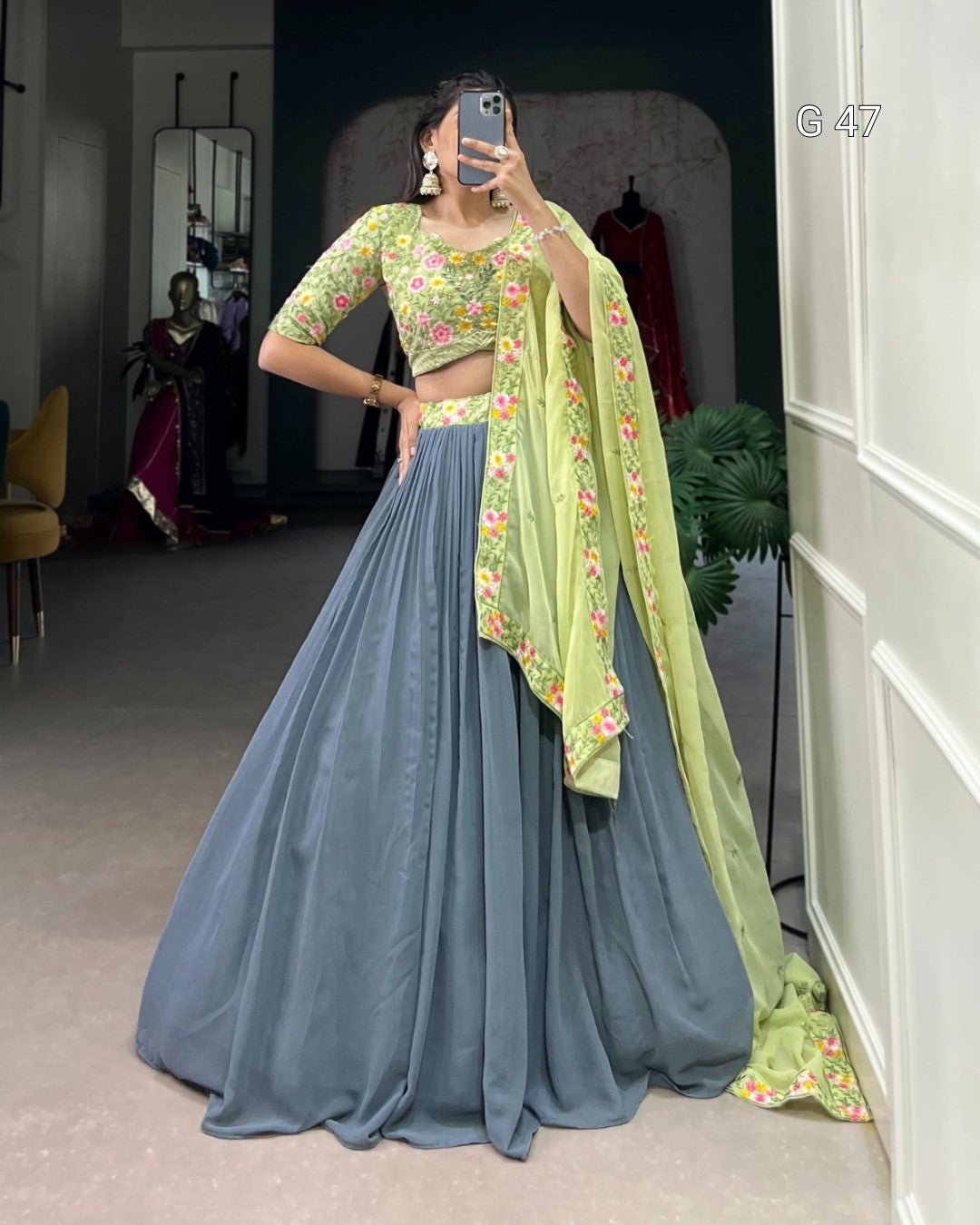 Woman wearing a traditional outfit with a green blouse and blue skirt in a room.
