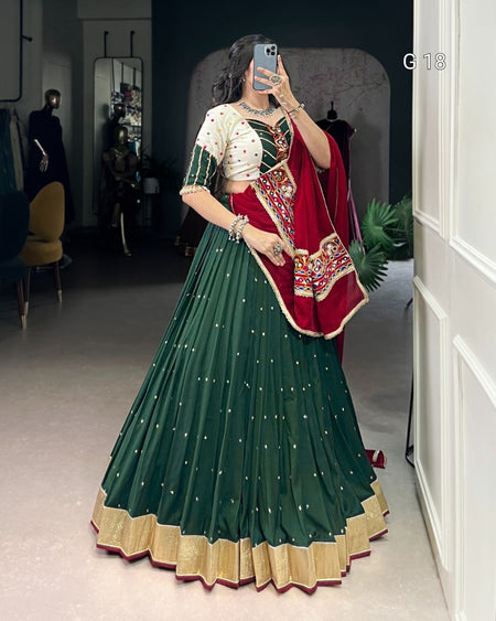 Person wearing a green and red traditional outfit in a room.